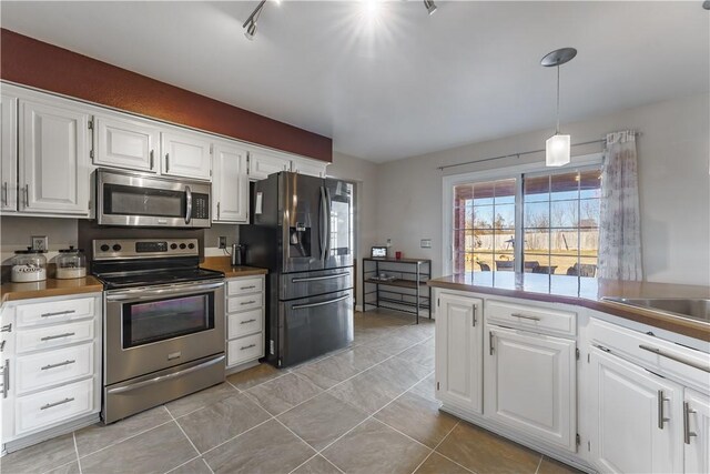 kitchen with light tile patterned floors, white cabinetry, appliances with stainless steel finishes, dark countertops, and decorative light fixtures