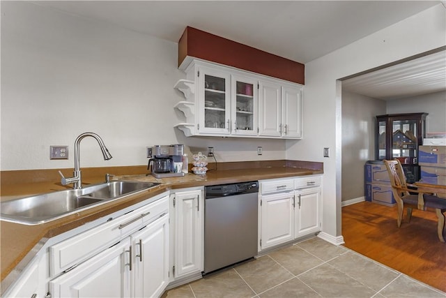 kitchen featuring light tile patterned floors, glass insert cabinets, white cabinetry, a sink, and dishwasher