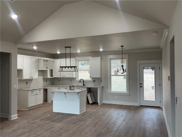 kitchen with vaulted ceiling, white cabinetry, hanging light fixtures, a center island, and light hardwood / wood-style floors