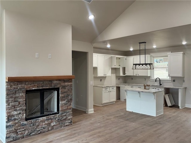 kitchen featuring pendant lighting, light stone counters, white cabinetry, and a center island