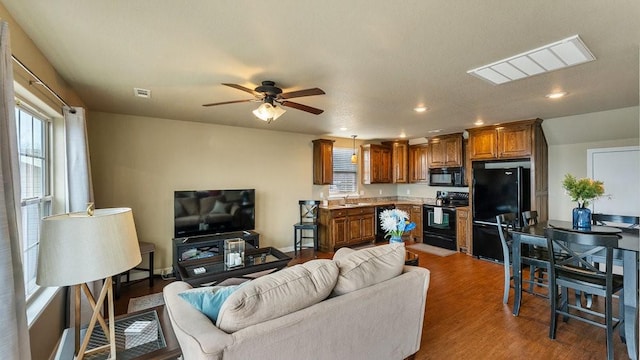 living room featuring hardwood / wood-style flooring, sink, and ceiling fan