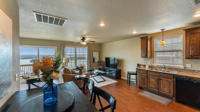 dining area featuring dark hardwood / wood-style floors, sink, ceiling fan, a water view, and a textured ceiling