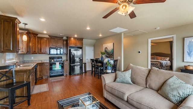 living room featuring sink, dark wood-type flooring, and ceiling fan