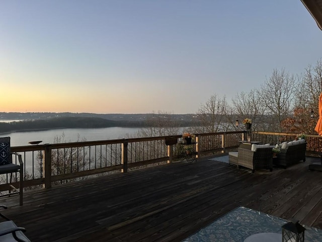 deck at dusk featuring a water view and outdoor lounge area