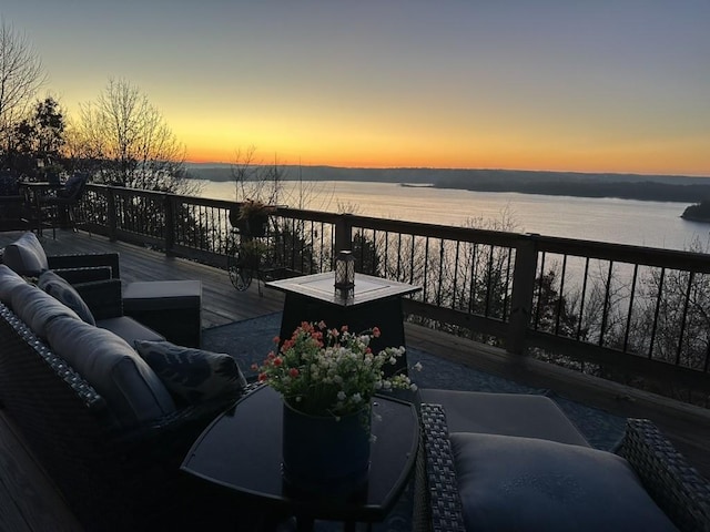 deck at dusk with outdoor lounge area and a water view