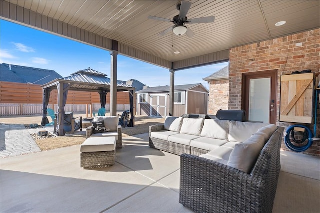 view of patio with an outdoor living space, a gazebo, ceiling fan, and a storage unit