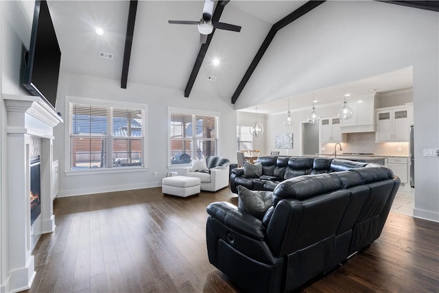 living room featuring beamed ceiling, dark hardwood / wood-style floors, sink, and high vaulted ceiling