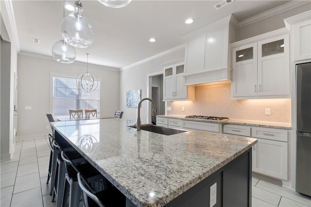 kitchen featuring appliances with stainless steel finishes, white cabinetry, sink, a large island with sink, and light stone counters