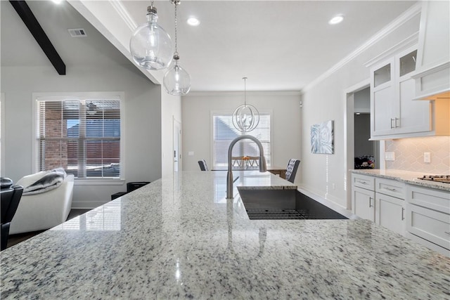 kitchen featuring light stone counters, crown molding, hanging light fixtures, decorative backsplash, and white cabinets