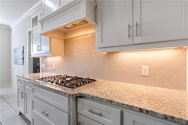 kitchen featuring premium range hood, light stone counters, ornamental molding, stainless steel gas cooktop, and decorative backsplash