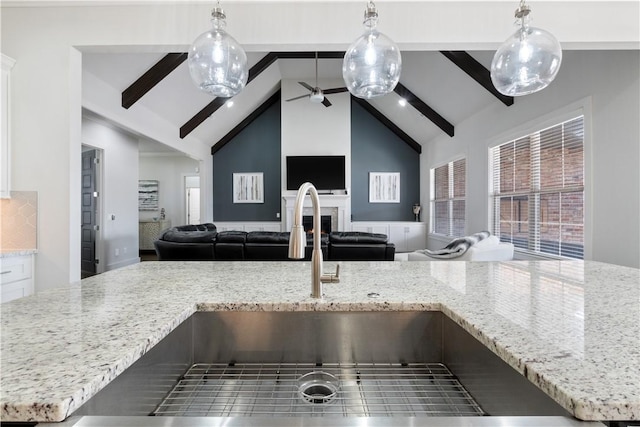 kitchen with high vaulted ceiling, sink, pendant lighting, and beam ceiling