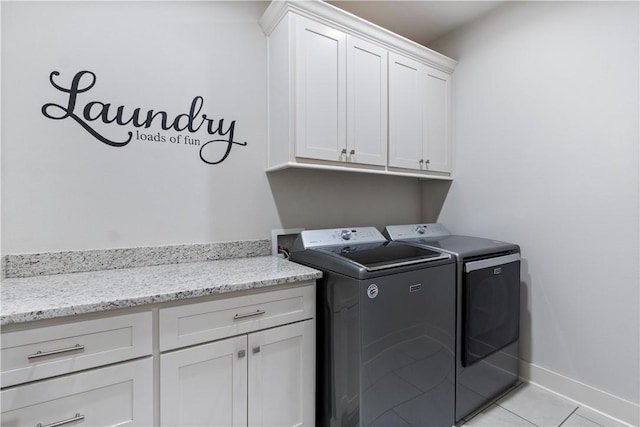 laundry room with cabinets, washer and clothes dryer, and light tile patterned floors