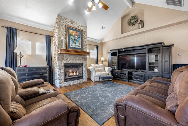 living room featuring high vaulted ceiling, beamed ceiling, ceiling fan, a fireplace, and hardwood / wood-style floors