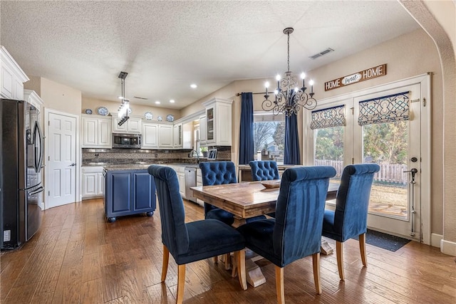 dining space featuring hardwood / wood-style flooring, a chandelier, and a textured ceiling