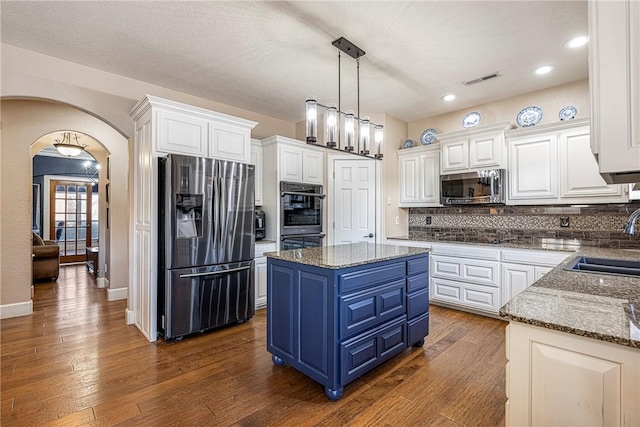 kitchen with blue cabinetry, stone countertops, a center island, stainless steel appliances, and white cabinets