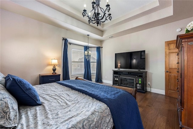 bedroom featuring dark wood-type flooring, a notable chandelier, and a tray ceiling