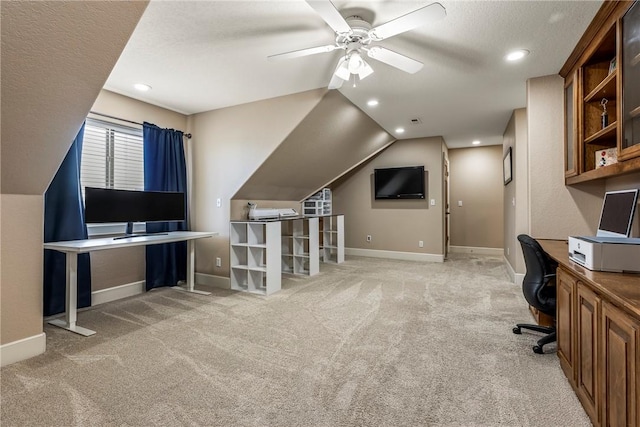 carpeted office space with ceiling fan, built in desk, vaulted ceiling, and a textured ceiling