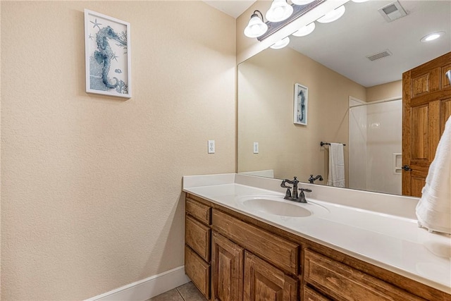 bathroom featuring vanity, a shower, and tile patterned floors