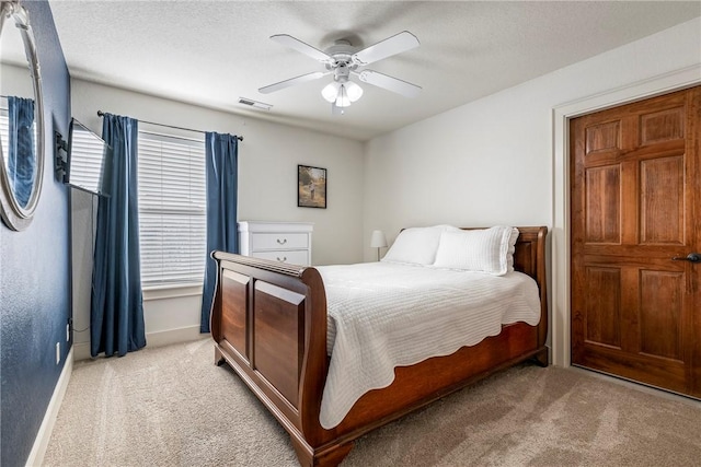 bedroom featuring ceiling fan, multiple windows, light carpet, and a textured ceiling