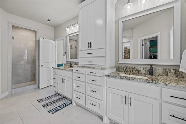 bathroom with a shower with door, vanity, and tile patterned flooring