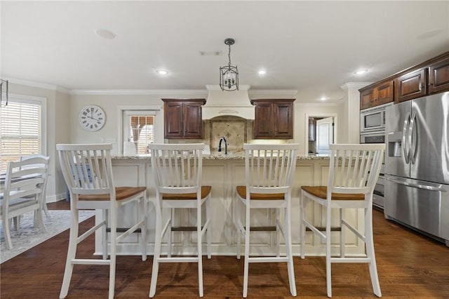 kitchen with pendant lighting, a kitchen island with sink, stainless steel appliances, dark hardwood / wood-style flooring, and custom exhaust hood