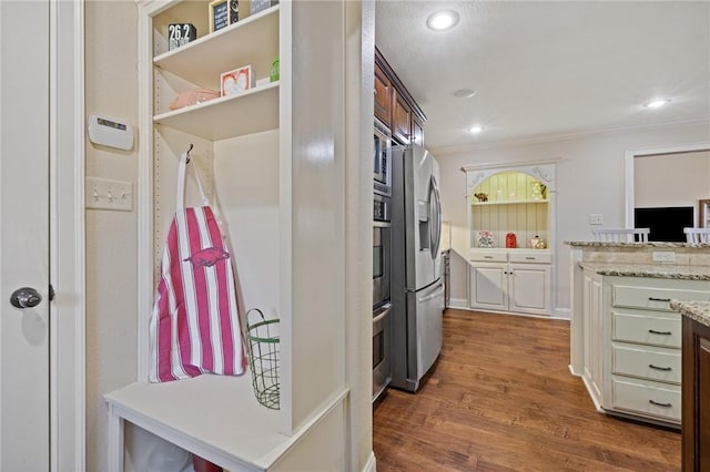 kitchen with light stone counters, stainless steel fridge, ornamental molding, and dark hardwood / wood-style floors