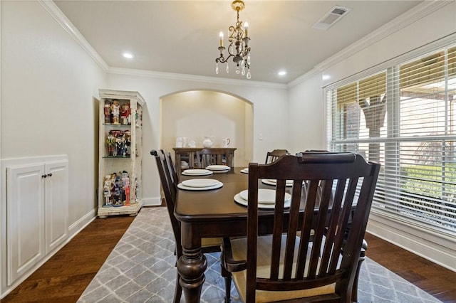 dining area with dark hardwood / wood-style flooring, crown molding, and an inviting chandelier