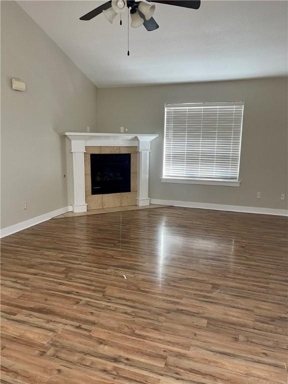 unfurnished living room with hardwood / wood-style flooring, a tile fireplace, and ceiling fan