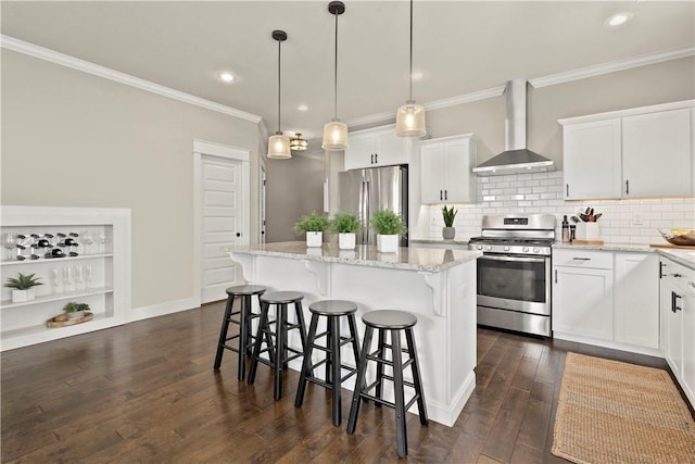 kitchen with stainless steel appliances, light stone counters, white cabinets, a kitchen island, and wall chimney exhaust hood