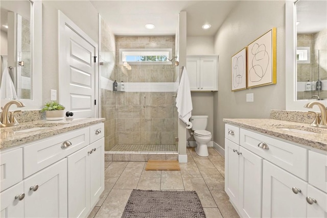 bathroom featuring vanity, toilet, tile patterned flooring, and a tile shower