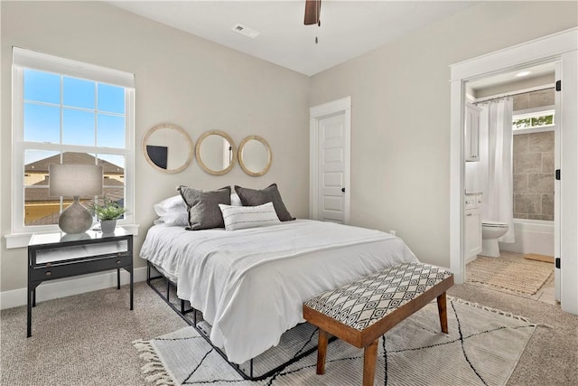 carpeted bedroom with multiple windows, ceiling fan, and ensuite bath