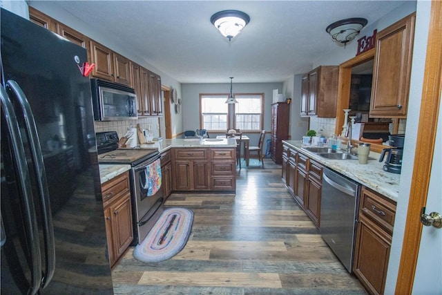 kitchen with sink, hanging light fixtures, kitchen peninsula, stainless steel appliances, and dark wood-type flooring