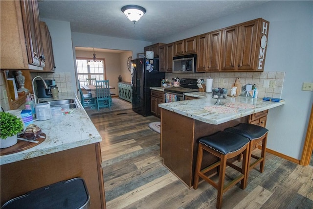 kitchen featuring appliances with stainless steel finishes, dark hardwood / wood-style floors, sink, decorative backsplash, and light stone counters