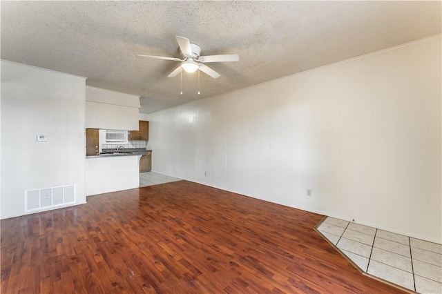 unfurnished living room featuring a textured ceiling, ceiling fan, and light hardwood / wood-style flooring