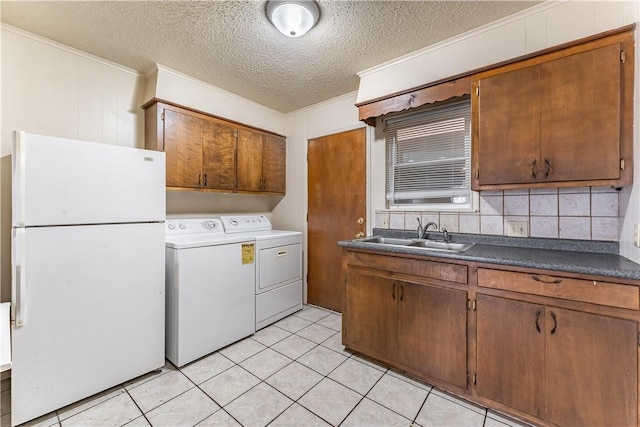 washroom featuring ornamental molding, separate washer and dryer, sink, and light tile patterned floors