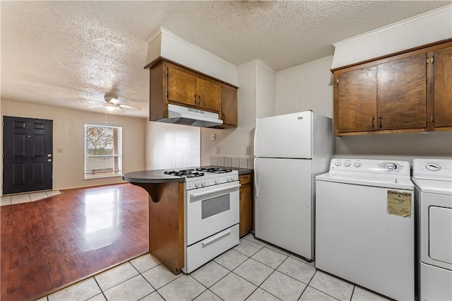 kitchen with light tile patterned flooring, washing machine and clothes dryer, white appliances, kitchen peninsula, and ceiling fan