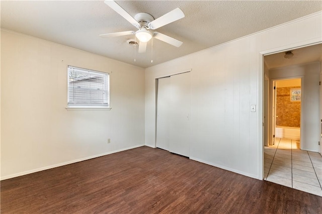 unfurnished bedroom with crown molding, ceiling fan, wood-type flooring, a textured ceiling, and a closet