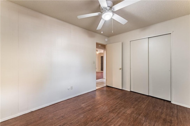 unfurnished bedroom featuring ornamental molding, dark wood-type flooring, a textured ceiling, and ceiling fan