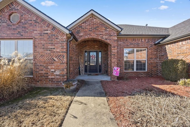 property entrance with brick siding and a shingled roof