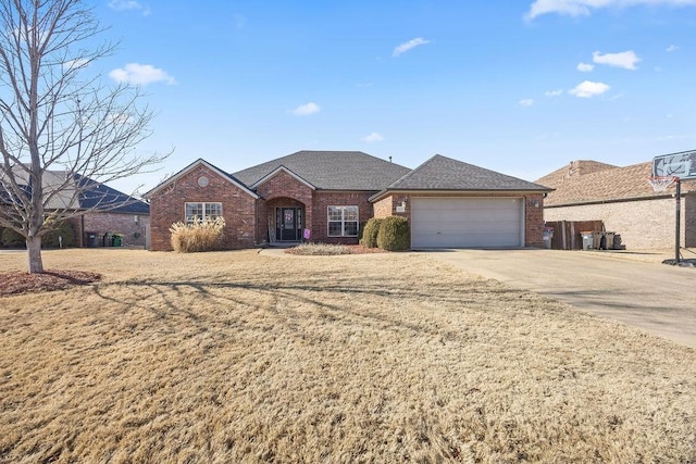 ranch-style home with concrete driveway, brick siding, a garage, and a front yard