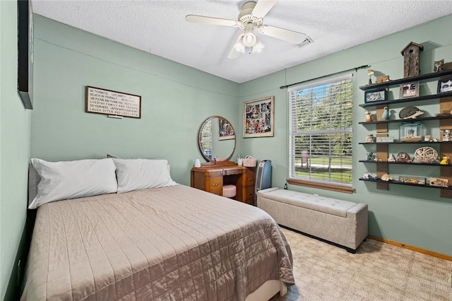 bedroom with ceiling fan, light colored carpet, and a textured ceiling