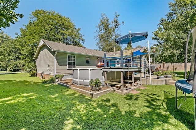 rear view of property featuring a fenced in pool, a yard, and a trampoline