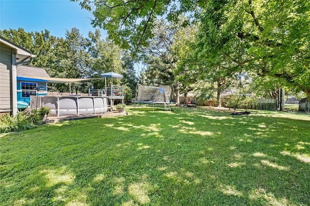 view of yard with a fenced in pool and a trampoline