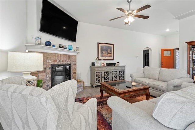 living room with hardwood / wood-style flooring, ceiling fan, and a fireplace