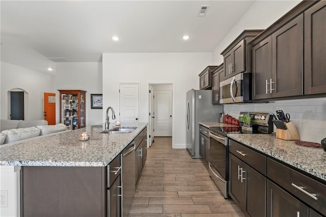 kitchen with tasteful backsplash, sink, light stone counters, and stainless steel appliances