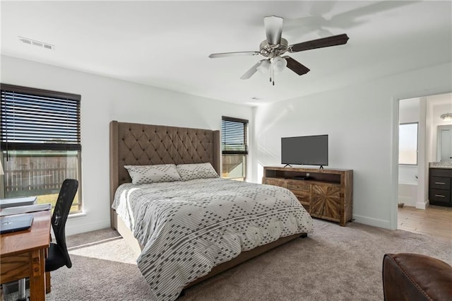 carpeted bedroom with ensuite bathroom and ceiling fan