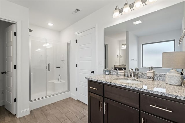 bathroom featuring hardwood / wood-style flooring, vanity, and a shower with door