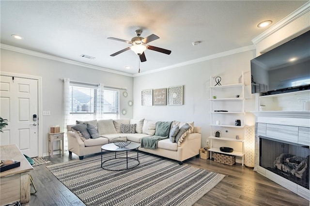 living room with dark hardwood / wood-style flooring, a fireplace, ornamental molding, and ceiling fan