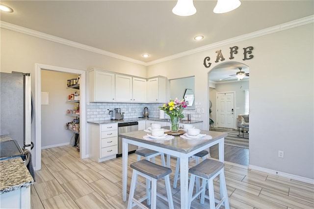 kitchen featuring backsplash, appliances with stainless steel finishes, light stone counters, and white cabinets