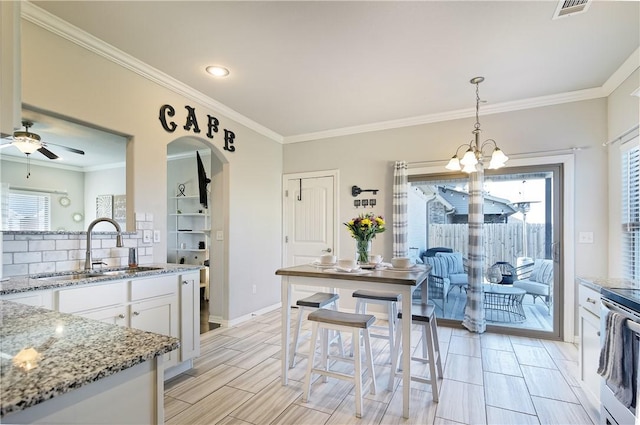 kitchen featuring white cabinetry, decorative light fixtures, sink, and light stone counters